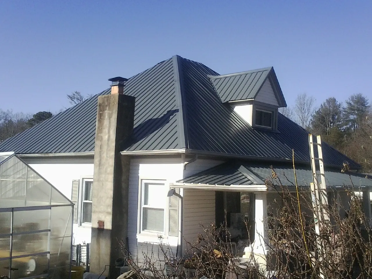 Dark blue standing seam metal roof on a white farmhouse with dormer — Slate & Tile Roof Repair by Roofing Brothers in Tell City