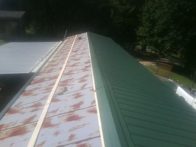 Old rusted panels beside newly installed green metal roofing — Wind Damage Roof Repair by Roofing Brothers in Tell City