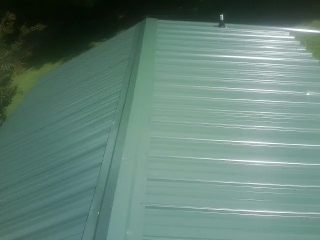 New green metal panels meeting at the ridge of a roof — Flat Roof Repair work by our crew in Tell City