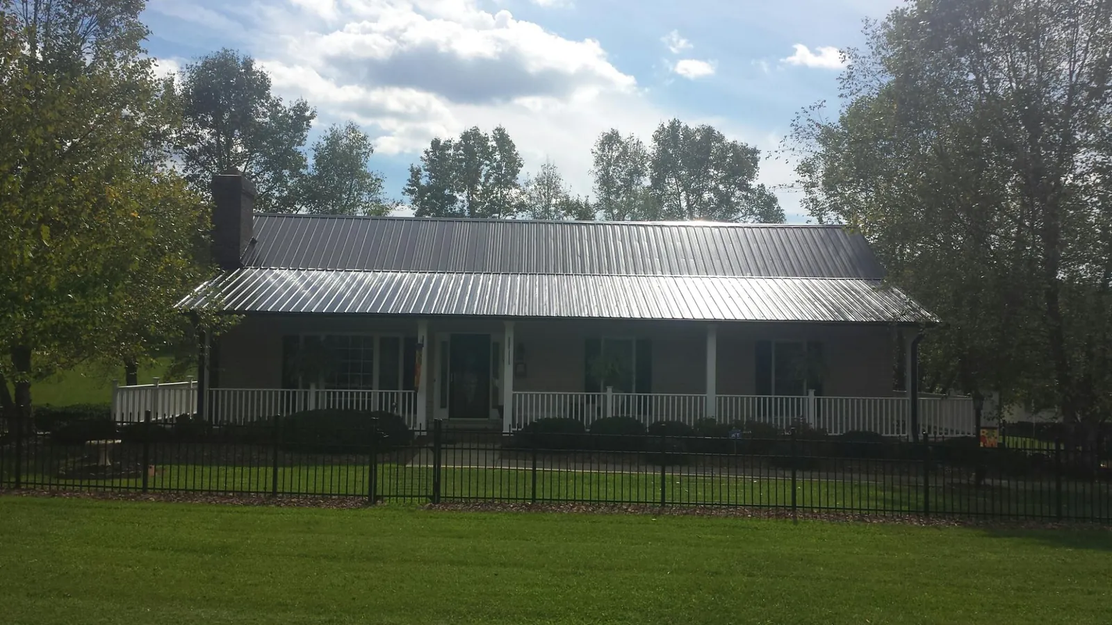 Gray metal roof on a brick ranch with a full width front porch — Gutter Guard Installation work by our crew in Tell City