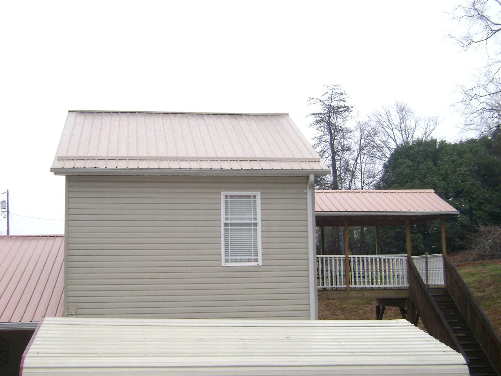 Tan metal roofs on a two story addition and attached porch, from a Roof Replacement job in Tell City
